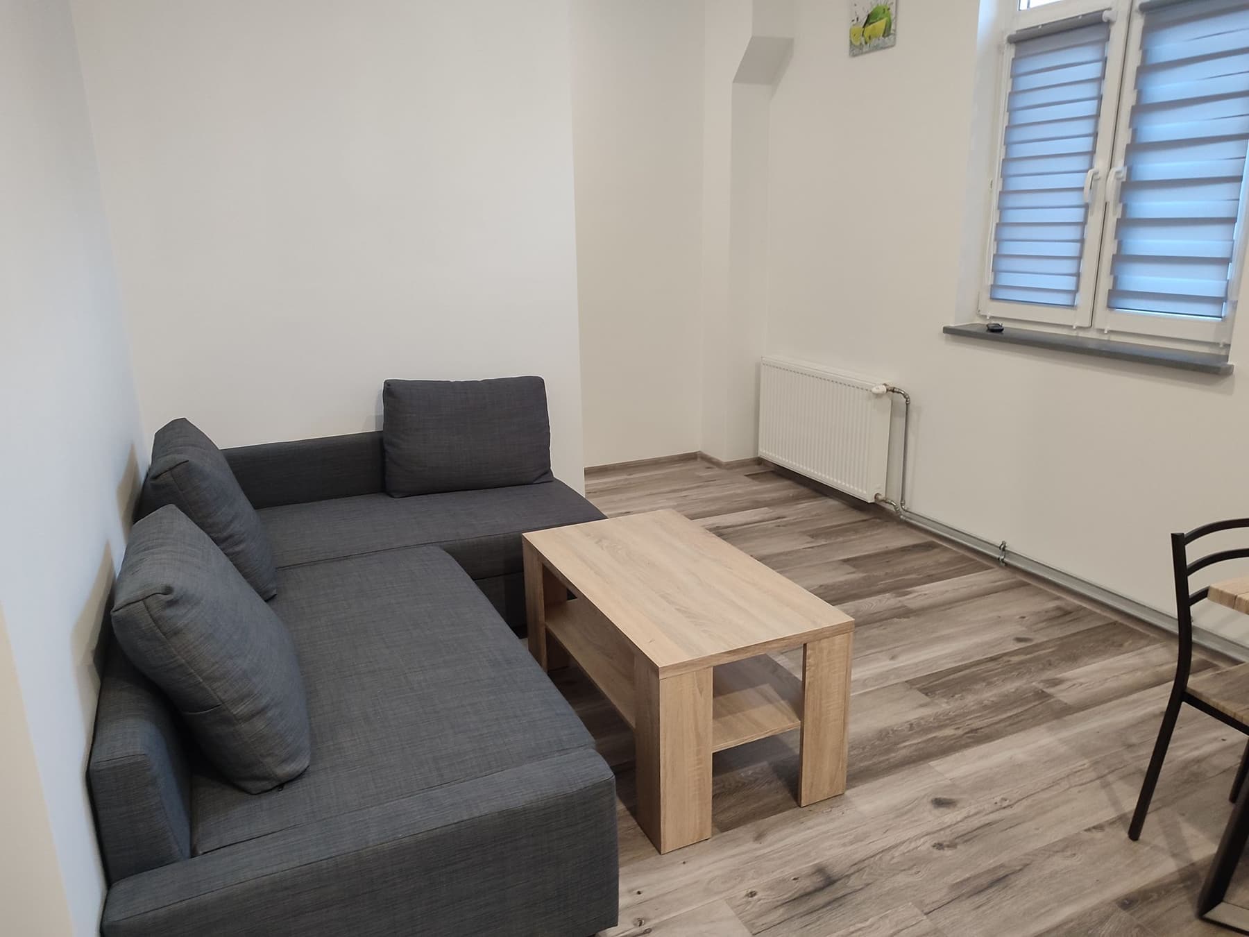 Salon z szarą kanapą i drewnianym stolikiem